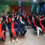 class of american tesol graduates raising their arms.